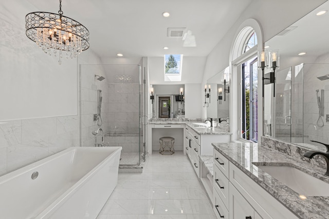 bathroom featuring marble finish flooring, a shower stall, a freestanding tub, recessed lighting, and a skylight
