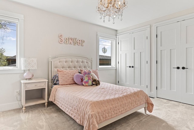 carpeted bedroom with multiple closets, multiple windows, a chandelier, and baseboards