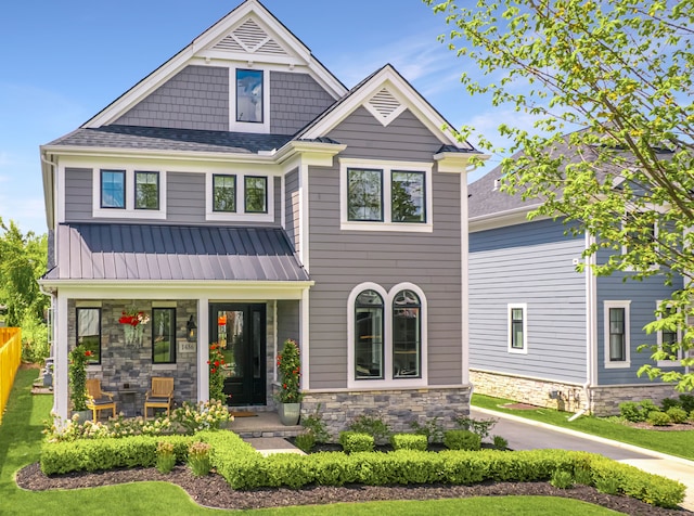 craftsman-style house featuring stone siding, a porch, metal roof, and roof with shingles