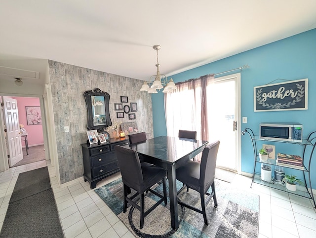 dining area with light tile patterned floors, a chandelier, and an accent wall