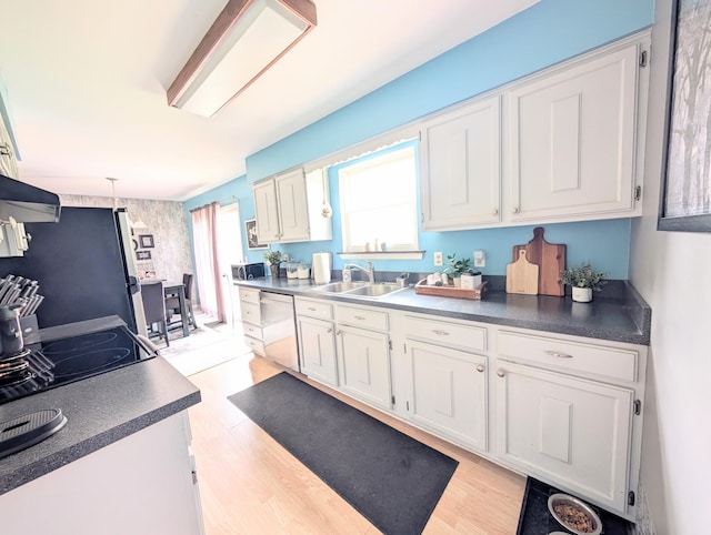 kitchen with a sink, stainless steel appliances, white cabinets, and light wood-type flooring
