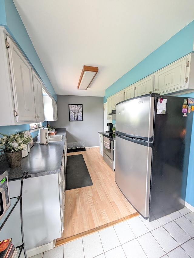 kitchen featuring appliances with stainless steel finishes, dark countertops, baseboards, and a sink