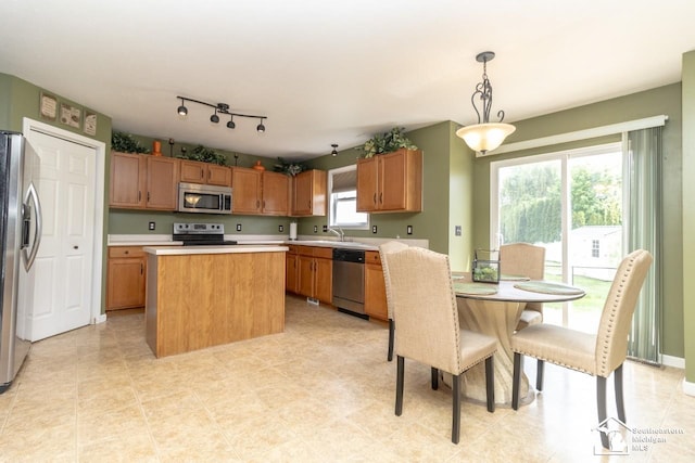 1786 Arbor Creek Dr, Monroe, MI 48162 - kitchen featuring appliances with stainless steel finishes, light countertops, a kitchen island, and brown cabinets