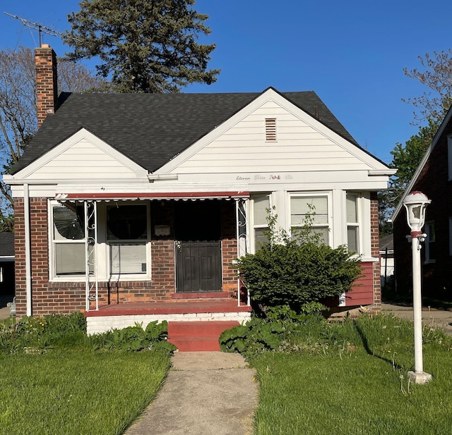 11336 Minock St, Detroit, MI 48228 - view of front facade with brick siding, a chimney, a shingled roof, and a front lawn