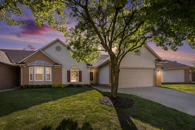 view of front of home with brick siding, a garage, concrete driveway, and a yard