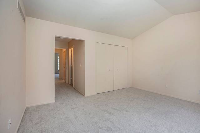unfurnished bedroom featuring light carpet, vaulted ceiling, and a closet