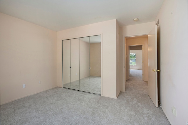 unfurnished bedroom with light colored carpet, a closet, and baseboards