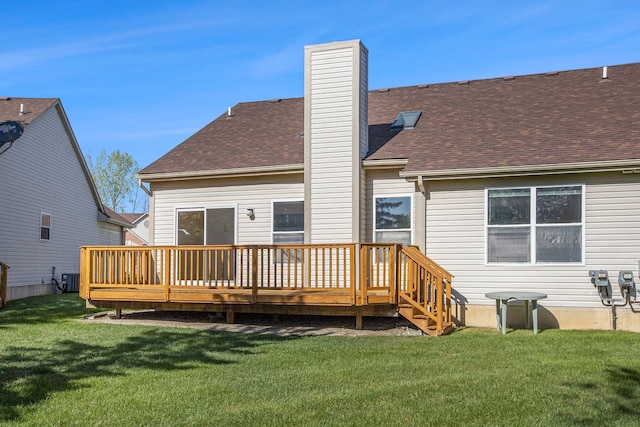 rear view of property featuring a wooden deck, a lawn, a chimney, and roof with shingles