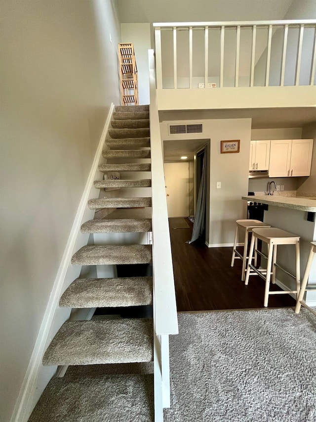 6210 Tennis Ct Unit D-11, Bay City, MI 48706 - stairway featuring baseboards, a towering ceiling, wood finished floors, and carpet floors