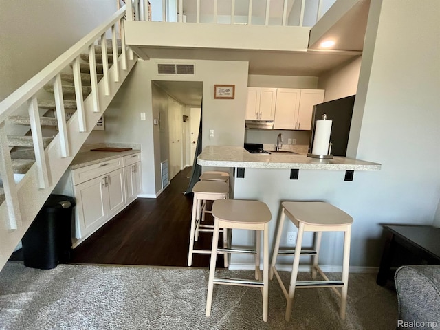 6210 Tennis Ct Unit D-11, Bay City, MI 48706 - kitchen with refrigerator, a high ceiling, a sink, a kitchen breakfast bar, and white cabinetry