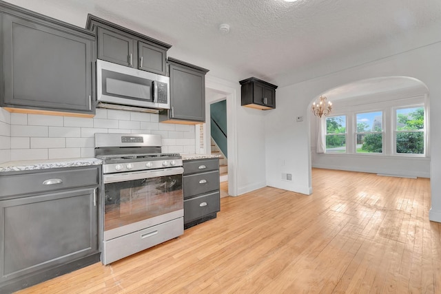 18600 Monica St, Detroit, MI 48221 - kitchen with stainless steel appliances, arched walkways, light wood-style floors, backsplash, and baseboards