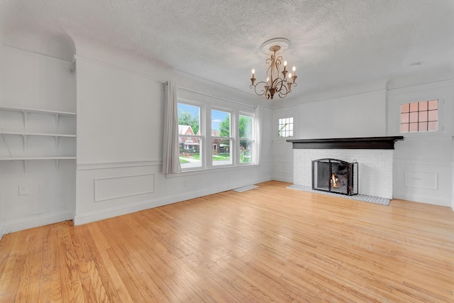 18600 Monica St, Detroit, MI 48221 - unfurnished living room with a chandelier, wood finished floors, a brick fireplace, and a textured ceiling