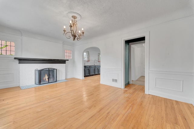 18600 Monica St, Detroit, MI 48221 - unfurnished living room featuring a decorative wall, arched walkways, light wood-style flooring, a sink, and a chandelier