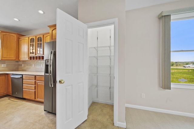 3605 Terrace Hills Ln, Jackson, MI 49203 - kitchen featuring stainless steel appliances, glass insert cabinets, light countertops, brown cabinetry, and backsplash