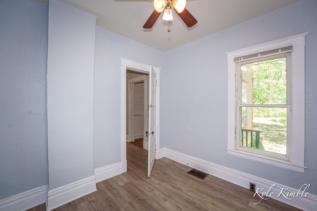 empty room featuring wood finished floors, baseboards, and ceiling fan