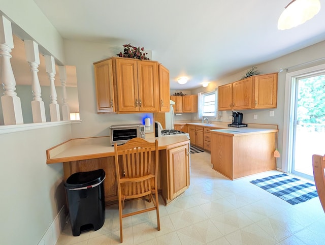 kitchen with a peninsula, a sink, light countertops, and light flooring