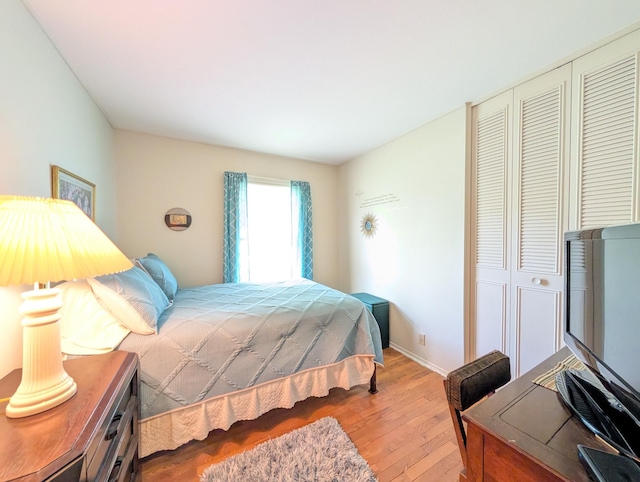 bedroom with a closet, hardwood / wood-style flooring, and baseboards