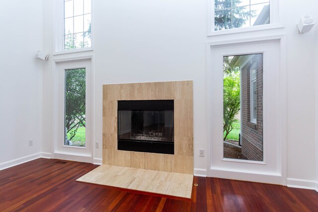 685 Dornoch Dr, Ann Arbor, MI 48103 - unfurnished living room featuring wood finished floors, plenty of natural light, a tiled fireplace, baseboards, and a high ceiling