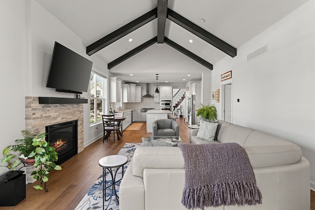 living room featuring stairs, light wood finished floors, a stone fireplace, and recessed lighting