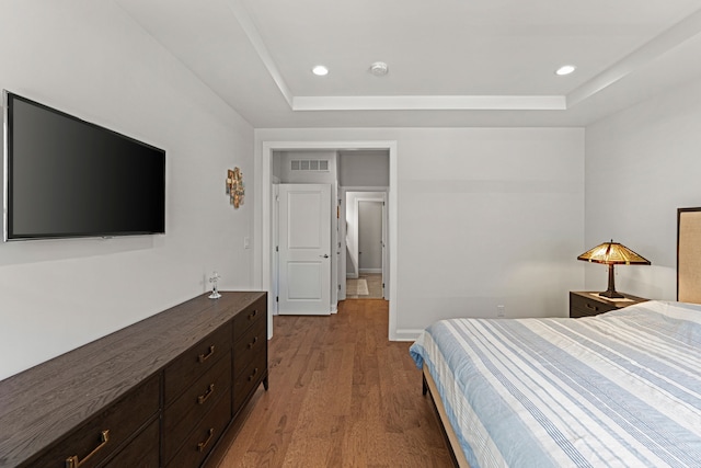 bedroom with a raised ceiling, light wood-type flooring, and recessed lighting