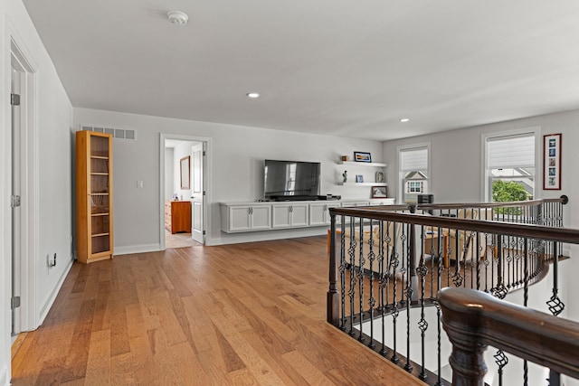 corridor featuring an upstairs landing, light wood-type flooring, baseboards, and recessed lighting