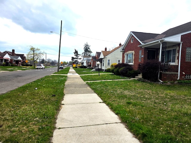 19183 Yonka St, Detroit, MI 48234 - view of asphalt road featuring sidewalks, street lights, traffic signs, and a residential view