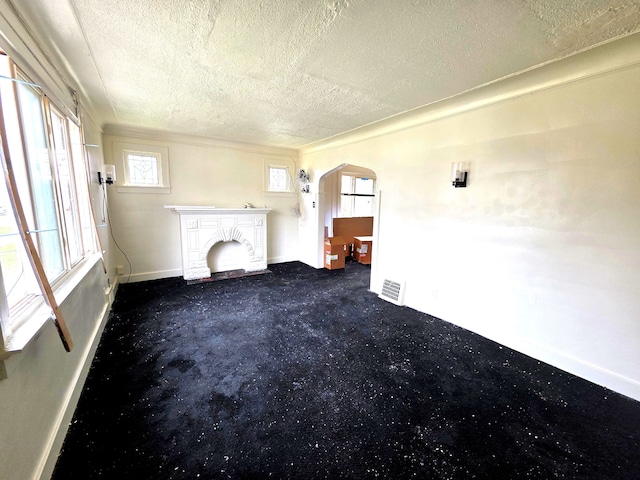 19183 Yonka St, Detroit, MI 48234 - unfurnished living room featuring arched walkways, a textured ceiling, baseboards, healthy amount of natural light, and carpet flooring