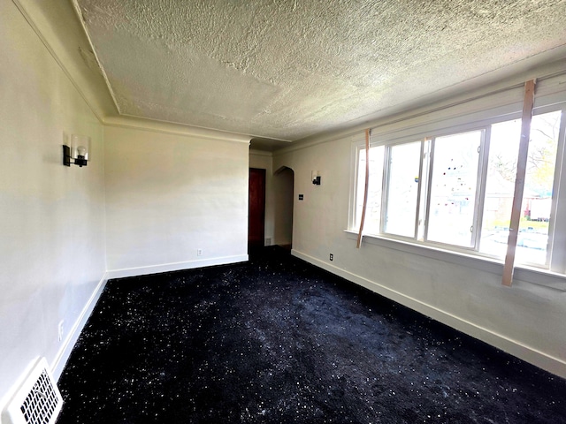 19183 Yonka St, Detroit, MI 48234 - unfurnished room featuring a textured ceiling, baseboards, arched walkways, and dark colored carpet