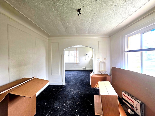 19183 Yonka St, Detroit, MI 48234 - corridor with a textured ceiling, arched walkways, carpet, and a decorative wall