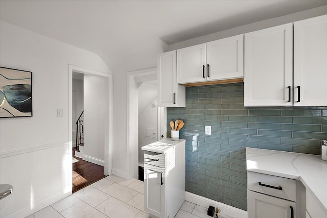 16573 Griggs St, Detroit, MI 48221 - kitchen with light stone counters, white cabinets, tasteful backsplash, light tile patterned floors, and vaulted ceiling