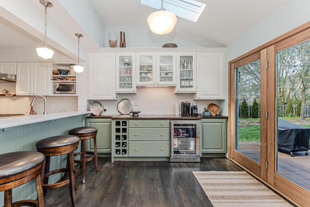 2142 Spring Ridge Dr, Ann Arbor, MI 48103 - bar area featuring wine cooler, vaulted ceiling, decorative light fixtures, stainless steel microwave, and a skylight