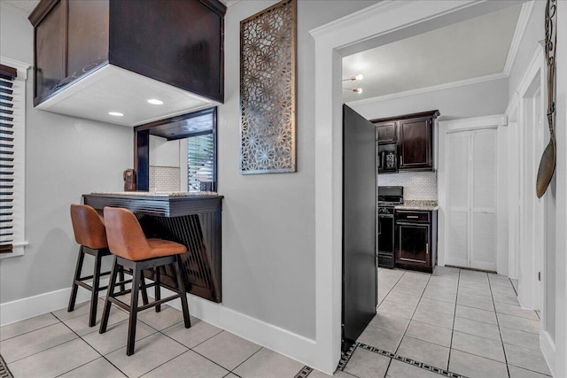 kitchen featuring baseboards, decorative backsplash, black appliances, light tile patterned floors, and dark brown cabinets