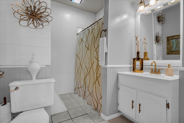 bathroom with tile patterned flooring, toilet, vanity, a shower with curtain, and wainscoting