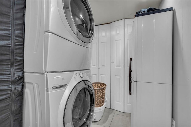laundry area featuring stacked washer / drying machine and tile patterned flooring