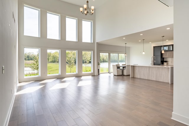 54598 Deadwood Ln, Utica, MI 48316 - unfurnished living room with a chandelier, a towering ceiling, wood finished floors, baseboards, and recessed lighting