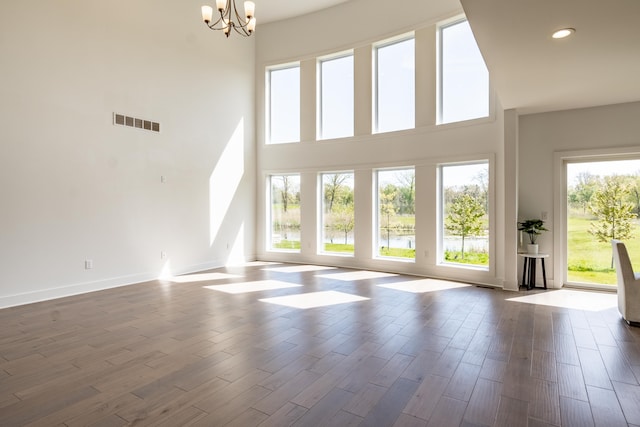 54598 Deadwood Ln, Utica, MI 48316 - unfurnished living room featuring a chandelier, a high ceiling, recessed lighting, dark wood-style floors, and baseboards