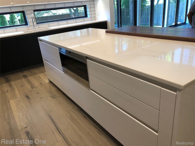 145 Westchester Way, Birmingham, MI 48009 - kitchen with modern cabinets, light wood-style flooring, light stone countertops, and white cabinetry