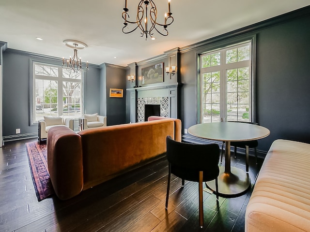 living area featuring a chandelier, ornamental molding, a baseboard heating unit, plenty of natural light, and dark wood-type flooring