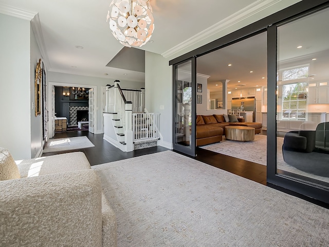 living area with a chandelier, wood-type flooring, ornamental molding, stairway, and recessed lighting