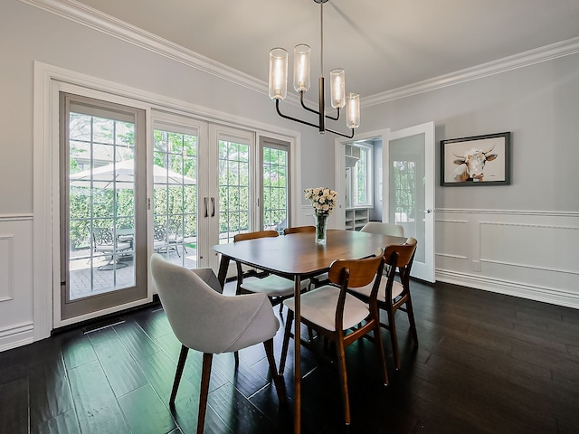 dining room with crown molding, a chandelier, dark wood-style flooring, and a wainscoted wall