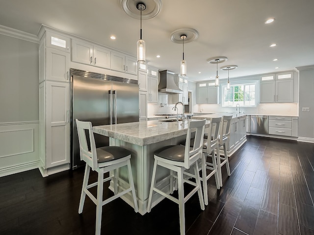 kitchen with wall chimney range hood, appliances with stainless steel finishes, glass insert cabinets, white cabinets, and recessed lighting