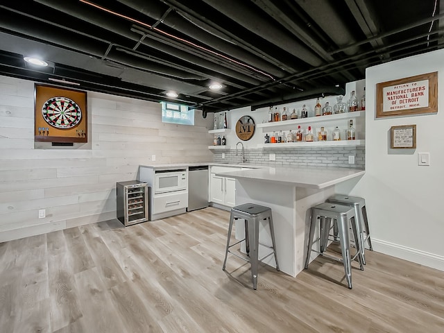 indoor bar with beverage cooler, light wood finished floors, wood walls, and fridge