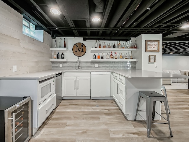 indoor wet bar featuring white appliances, beverage cooler, and light wood finished floors