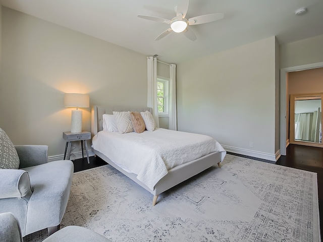 bedroom featuring baseboards, wood finished floors, and ceiling fan