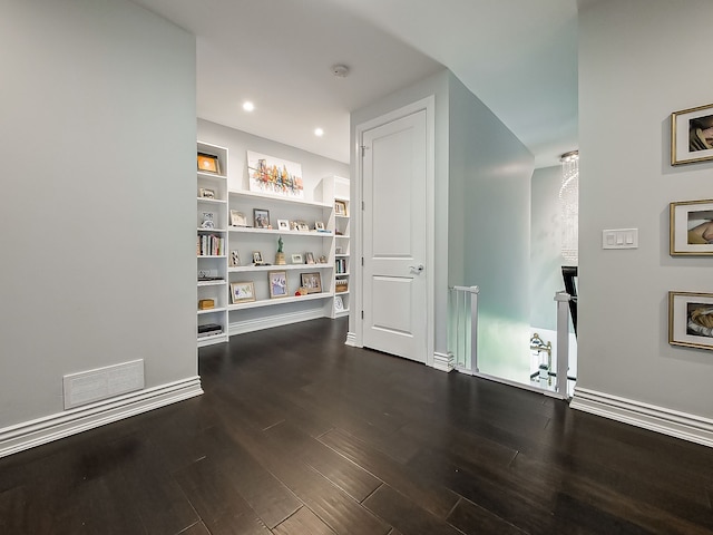 hallway featuring dark wood-style floors, built in shelves, baseboards, and recessed lighting