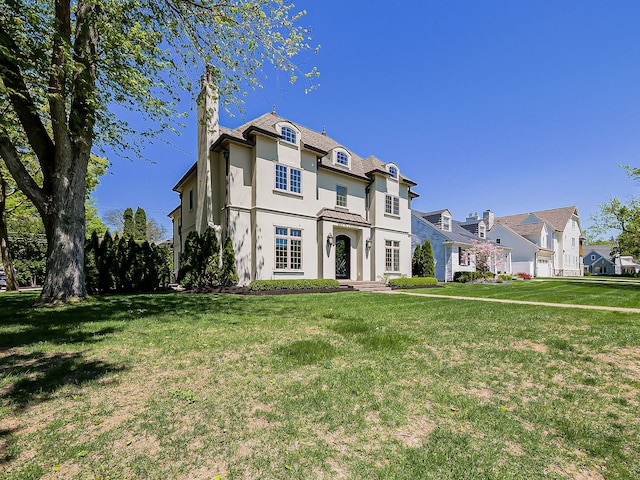 french country style house featuring a chimney, stucco siding, a front lawn, and a residential view