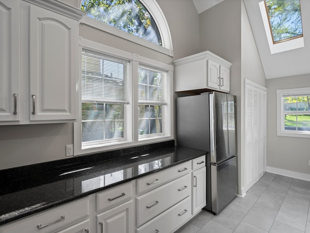 270 S Center St, Northville, MI 48167 - kitchen featuring vaulted ceiling, freestanding refrigerator, a skylight, white cabinets, and dark stone counters