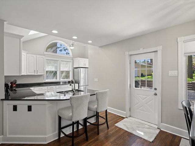 270 S Center St, Northville, MI 48167 - kitchen featuring a sink, freestanding refrigerator, dark countertops, a peninsula, and white cabinets