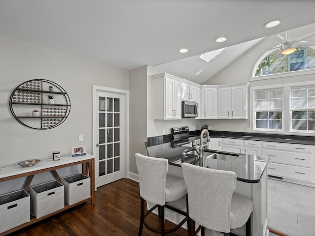 270 S Center St, Northville, MI 48167 - kitchen featuring appliances with stainless steel finishes, a skylight, a kitchen breakfast bar, lofted ceiling, and white cabinetry