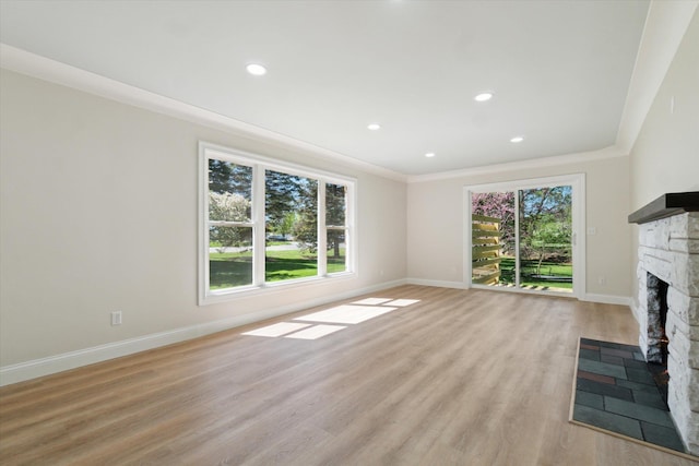1431 E Oliver St, Owosso, MI 48867 - unfurnished living room featuring a stone fireplace, light wood finished floors, baseboards, ornamental molding, and recessed lighting